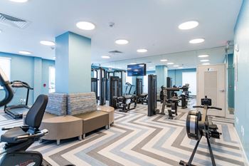 a gym with weights and cardio machines and a tv